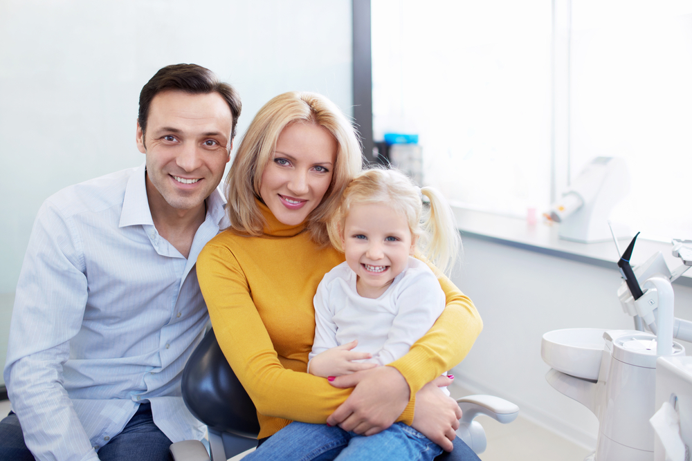 family with young girl smiling at dental office
