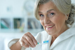 Old woman holding toothbrush up to mouth