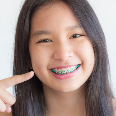 Young girl smiling and pointing to her braces