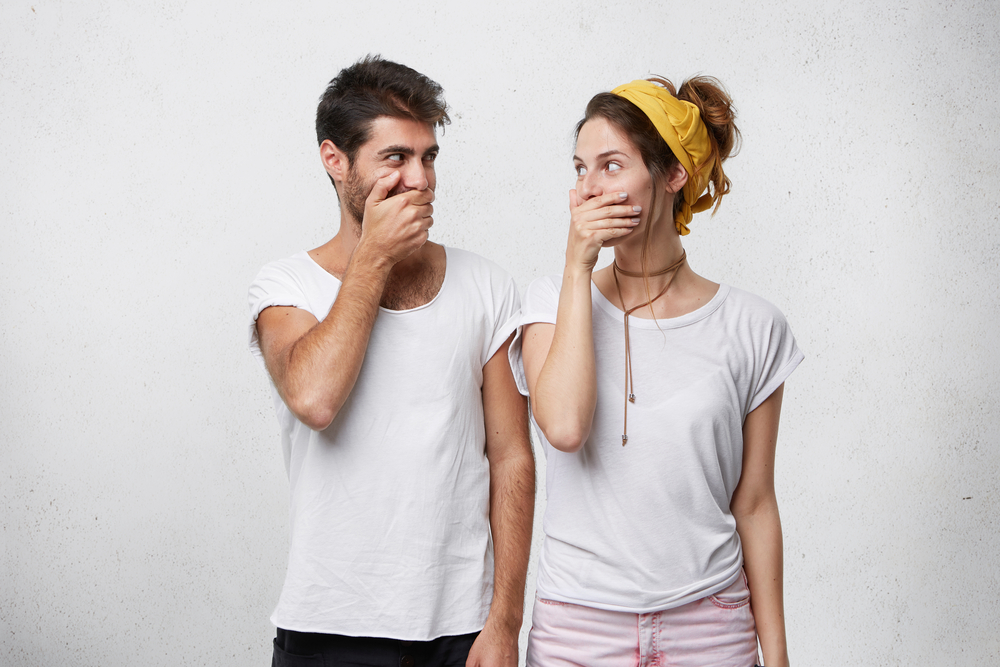 man and woman covering their mouths