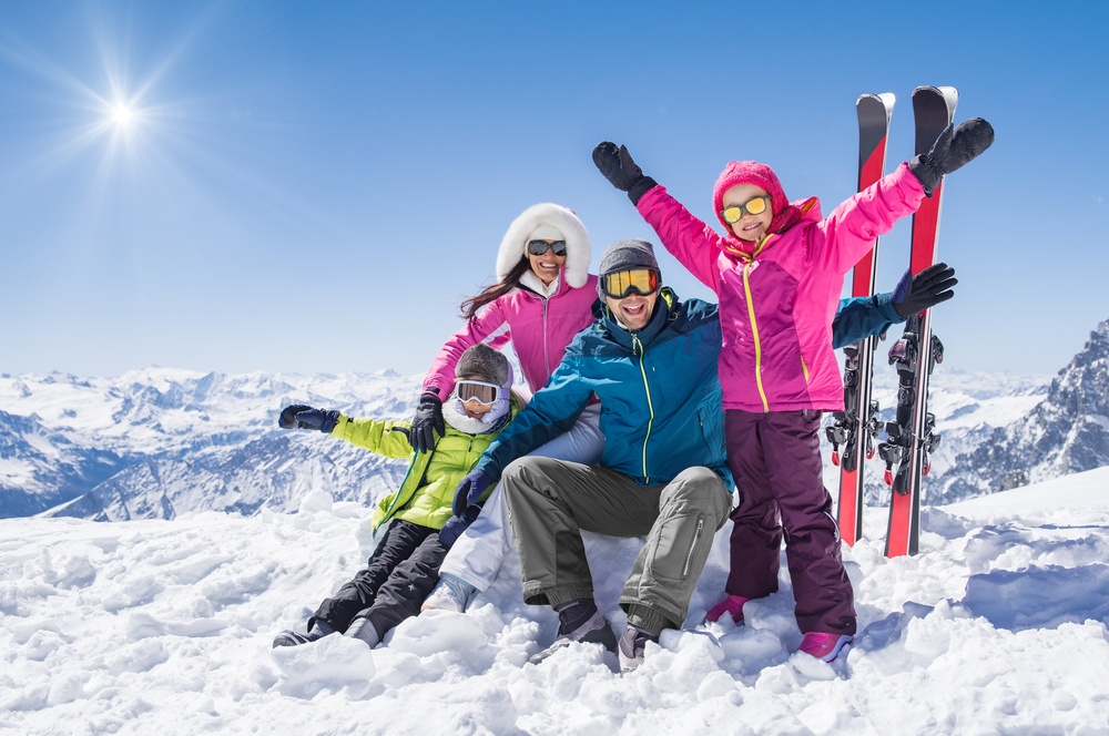 Family on top of mountain skiing in sunshine